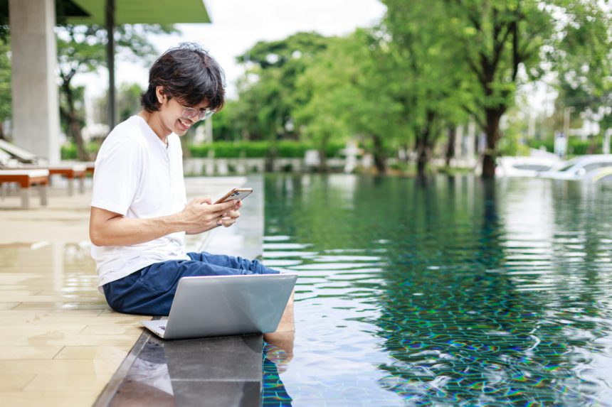 Man Working Poolside on Vacation Balances Business and Relaxation with Laptop