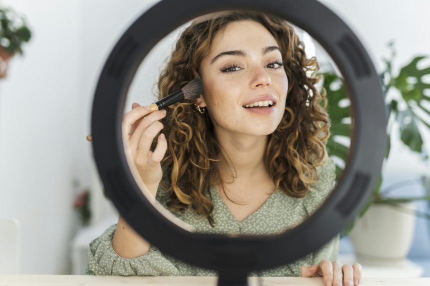 pretty woman putting on makeup at home with light