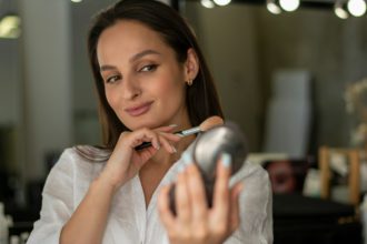 Process of making makeup woman does makeup and looks at her reflection in the mirror