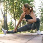 Warm up routine. Attractive middle aged athletic woman in sportswear looking away, stretching her